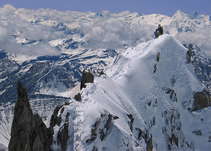 foto di alpinista seduto sulla neve della cima della montagna