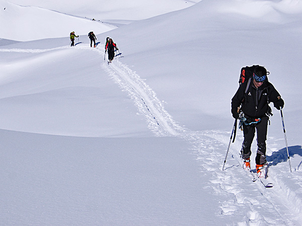 foto di scialpinisti che avanzano in fila sul manto nevoso