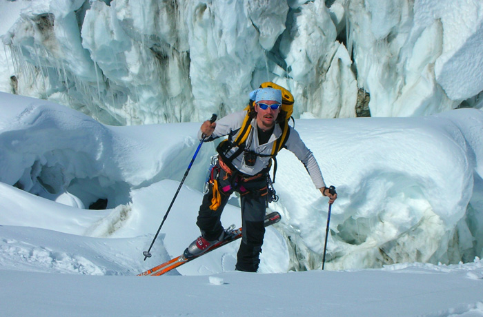 scialpinista solitario avanza con gli sci ai piedi foto di un scialpinista solitario in salita con sfondo una parete di neve e ghiaccio