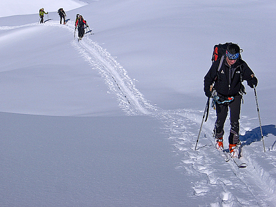 gruppo di scialpinisti in salita con gli sci sulla distesa di neve
